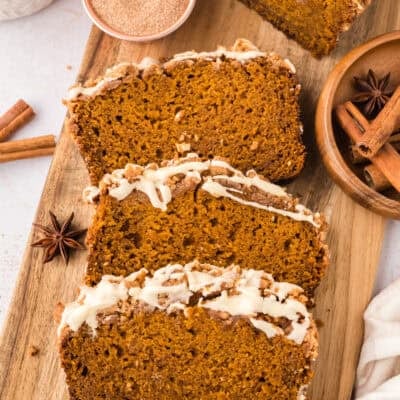 Slices of pumpkin bread with streusel topping and glaze on cutting board.
