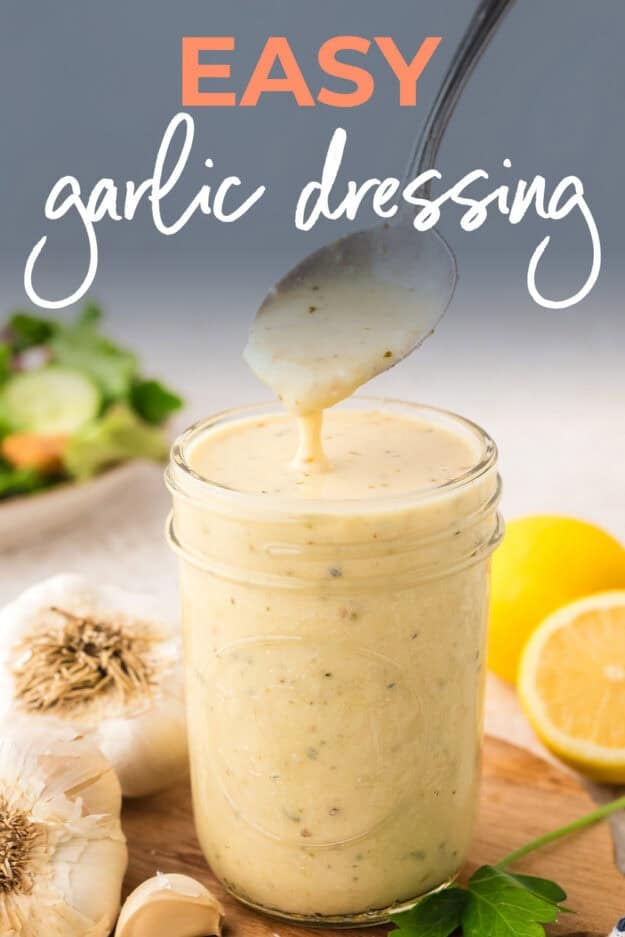 Garlic dressing dripping off a spoon into a mason jar.
