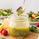 Homemade Italian dressing dripping off spoon into mason jar.
