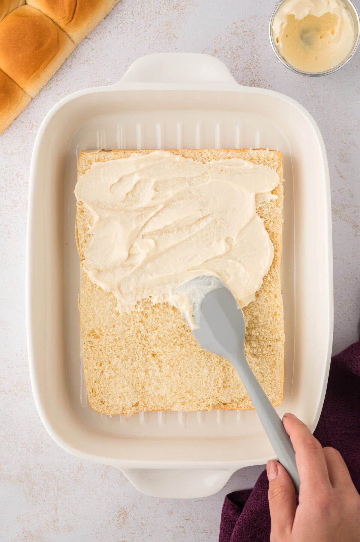 Mayonnaise being spread on slider buns.