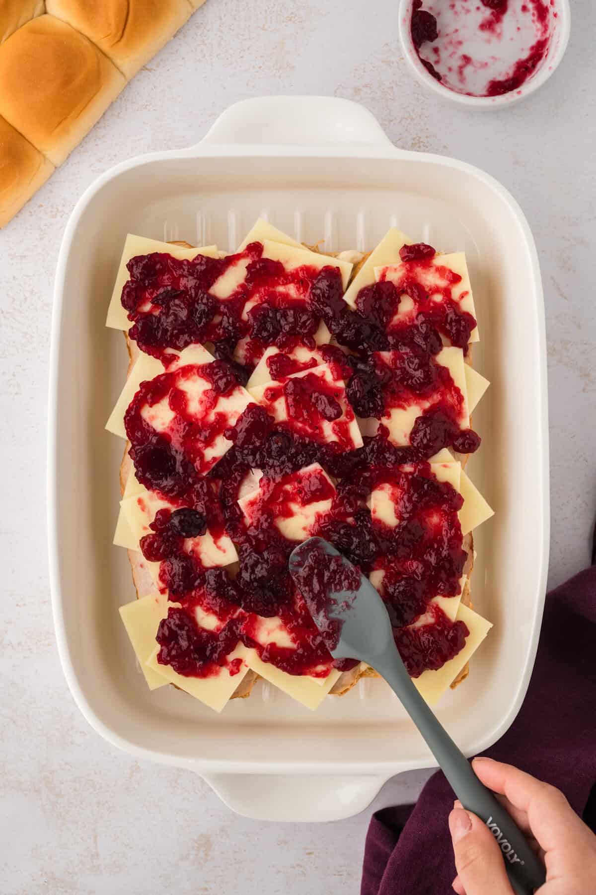Cranberry sauce being spread on sliders.