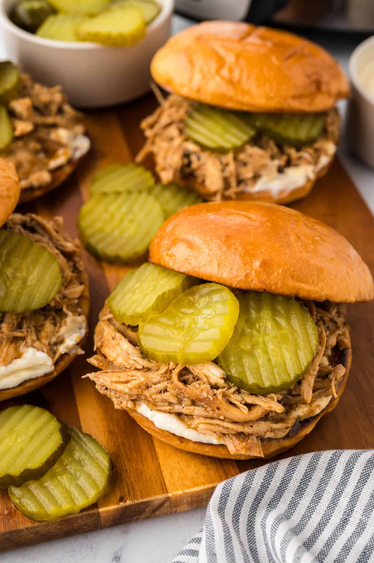 Sandwiches topped with shredded Nashville hot chicken, pickles, and mayo.