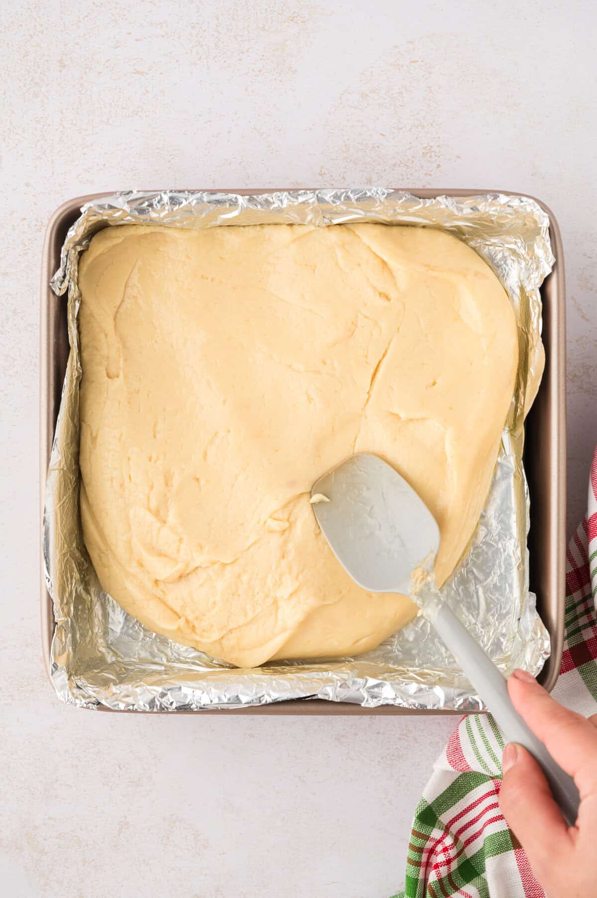 Fudge being spread into foil lined pan.