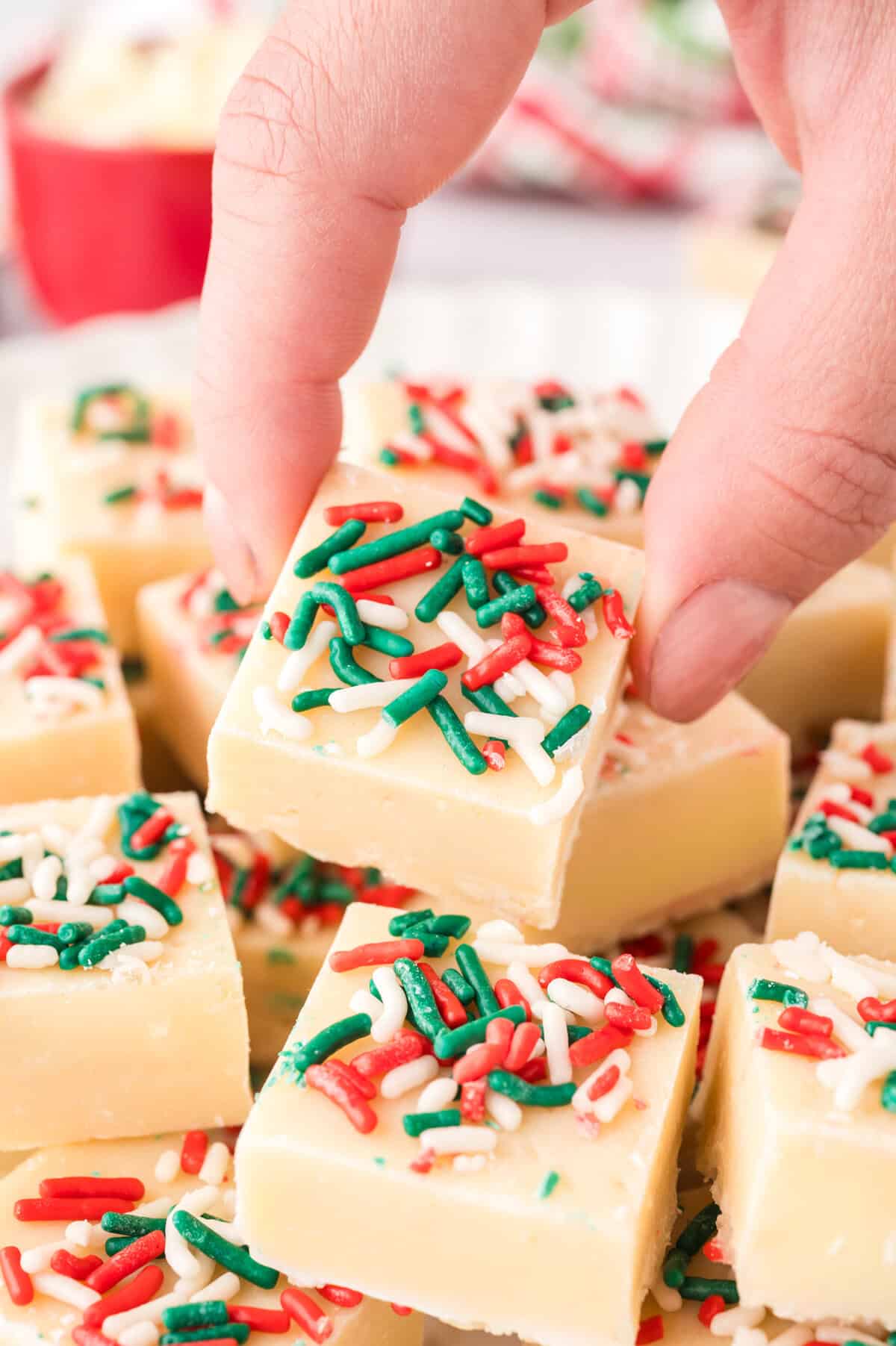 Hand grabbing a piece of sugar cookie fudge.