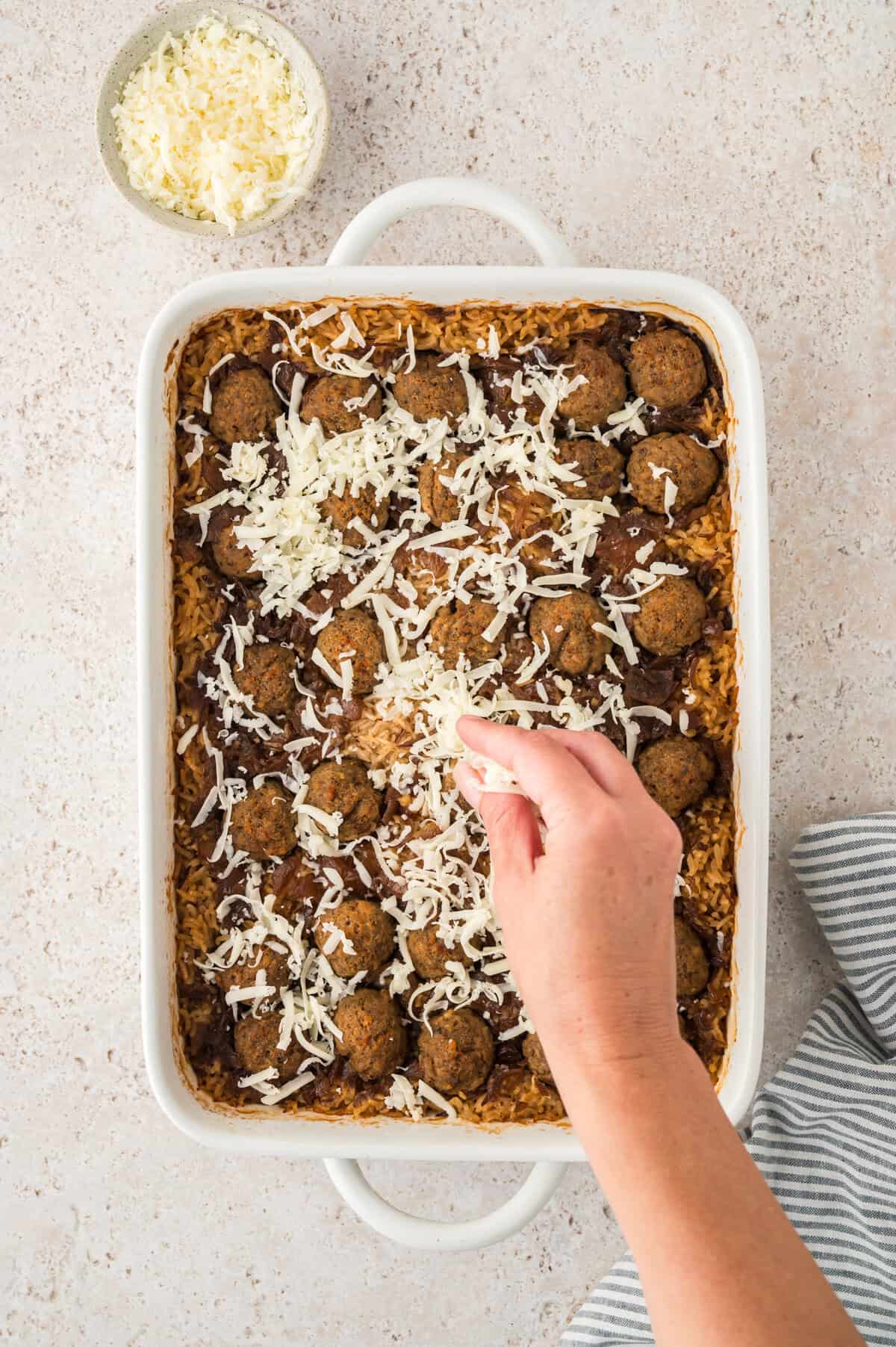 Shredded cheese being sprinkled over 9x13 dish.