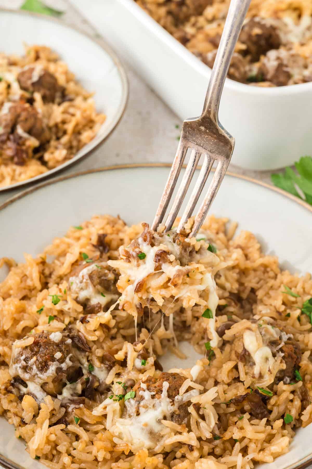 Plate topped with meatballs and rice and cheese.