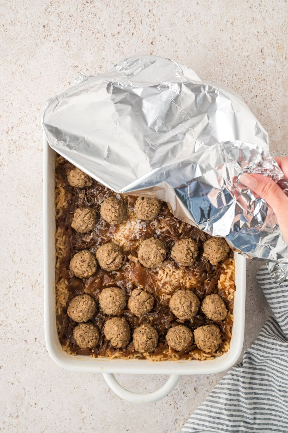 Foil being removed from baked rice recipe.