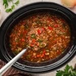 Stuffed pepper soup in slow cooker with a ladle.