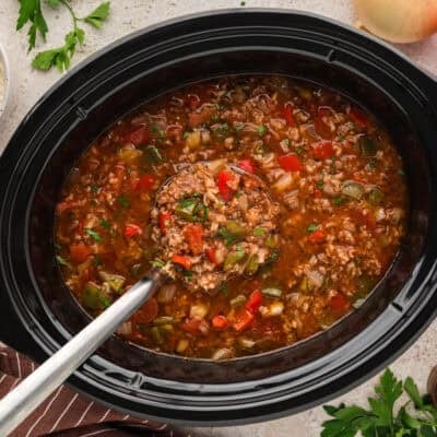 Stuffed pepper soup in slow cooker with a ladle.