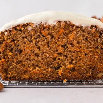 Loaf of carrot cake bread topped with cream cheese frosting.