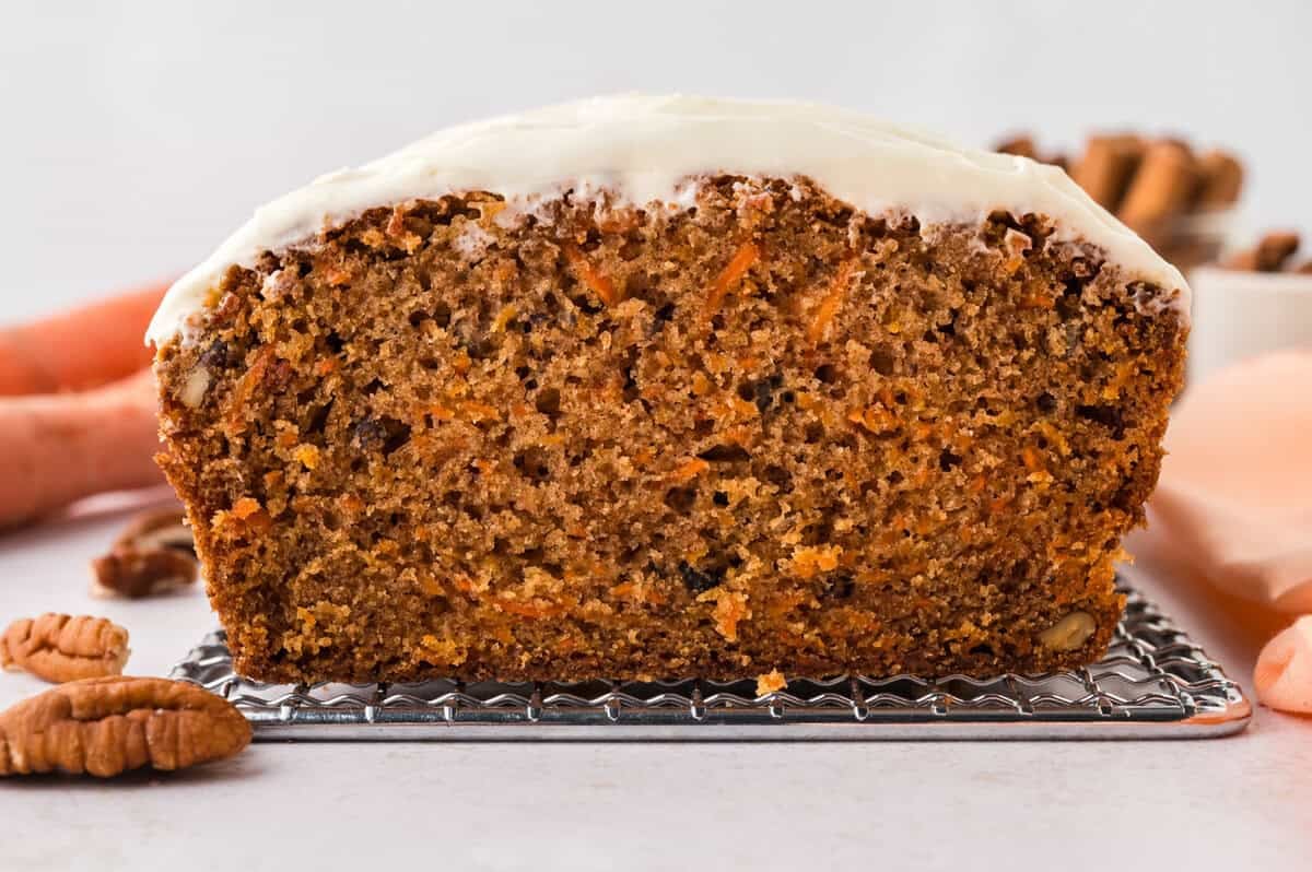 Loaf of carrot cake bread topped with cream cheese frosting.