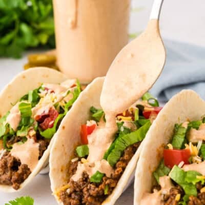 Taco Bell creamy jalapeno sauce being drizzled over taco.