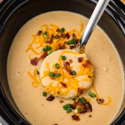 Crockpot potato soup made with hashbrowns on ladle over slow cooker.