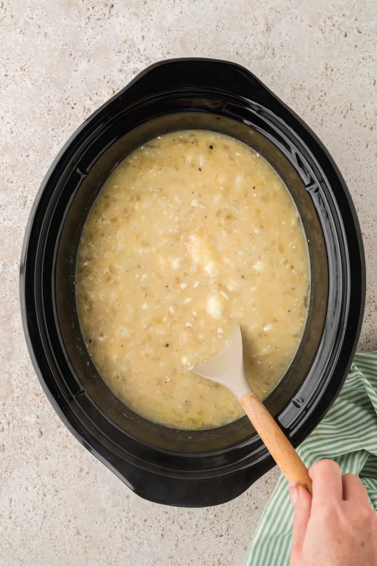 Crockpot potato soup with hasbrowns being stirred.