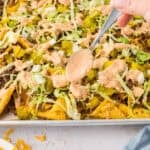 Spoon drizzling Big Mac sauce over nachos.