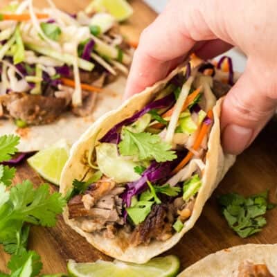 Hand holding a taco filled with cilantro lime slaw.