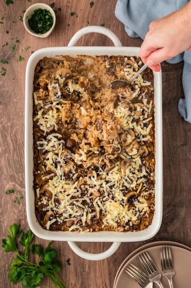 Cheesy rice being stirred in baking dish.