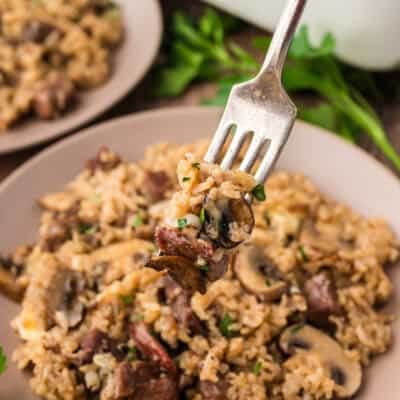 Rice on a fork with steak and mushrooms.