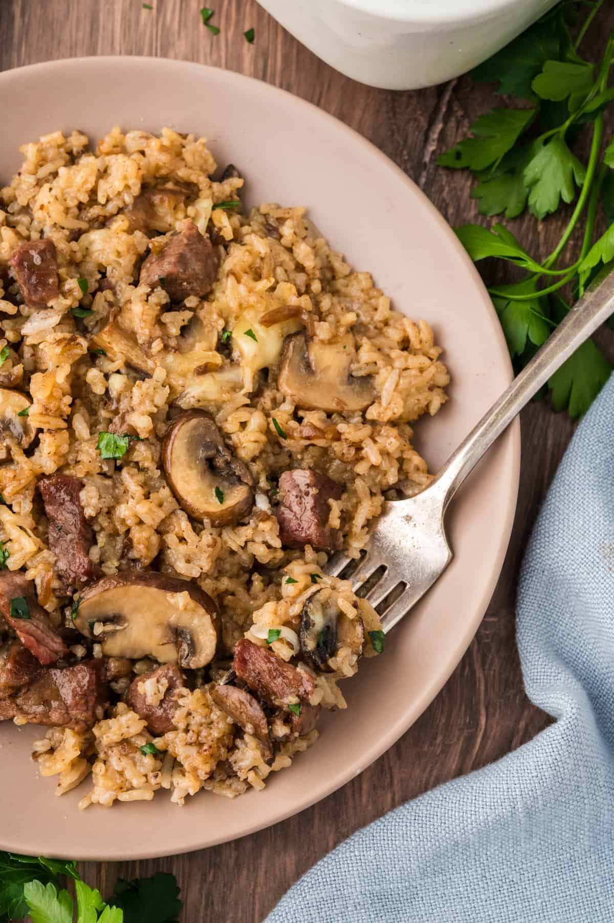 Plate full of baked rice with steak and mushrooms.