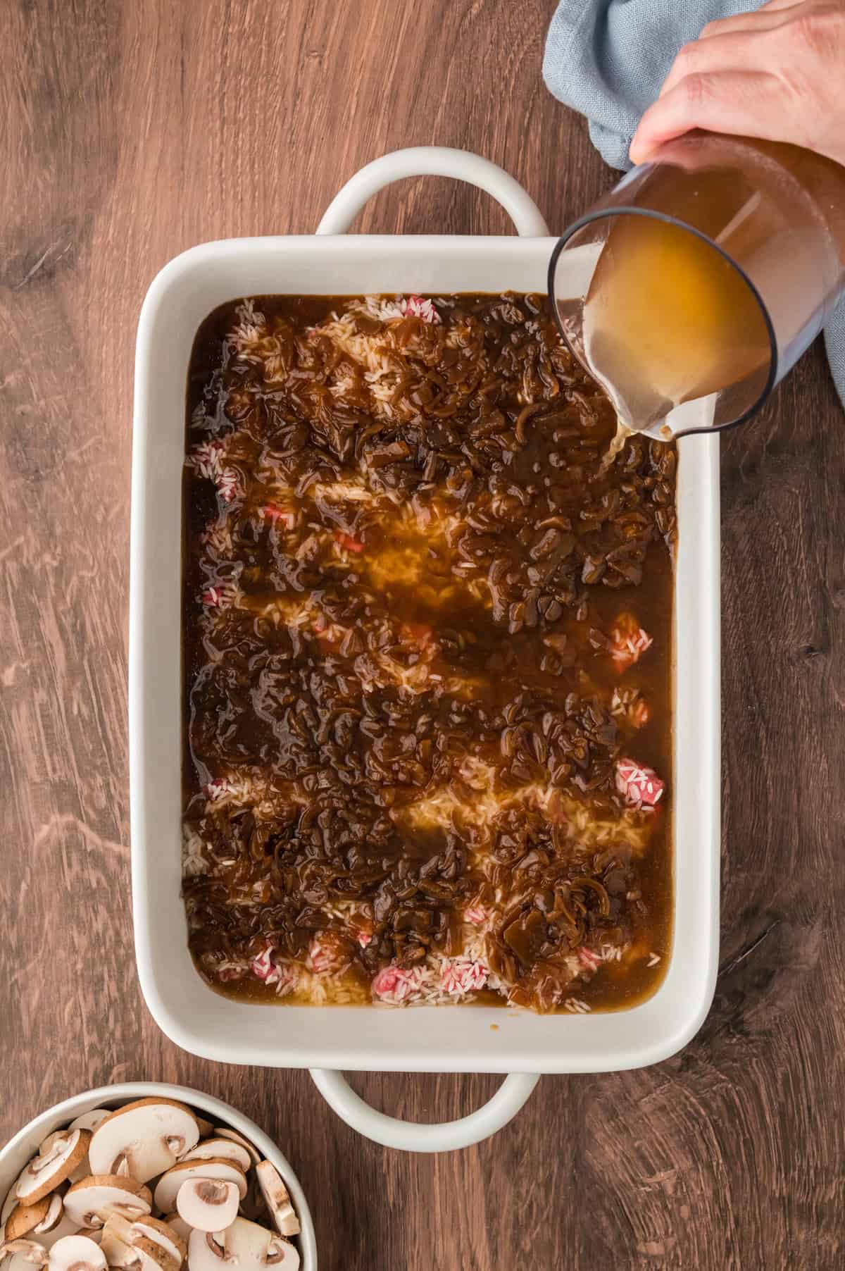 Broth being poured over rice in dish.