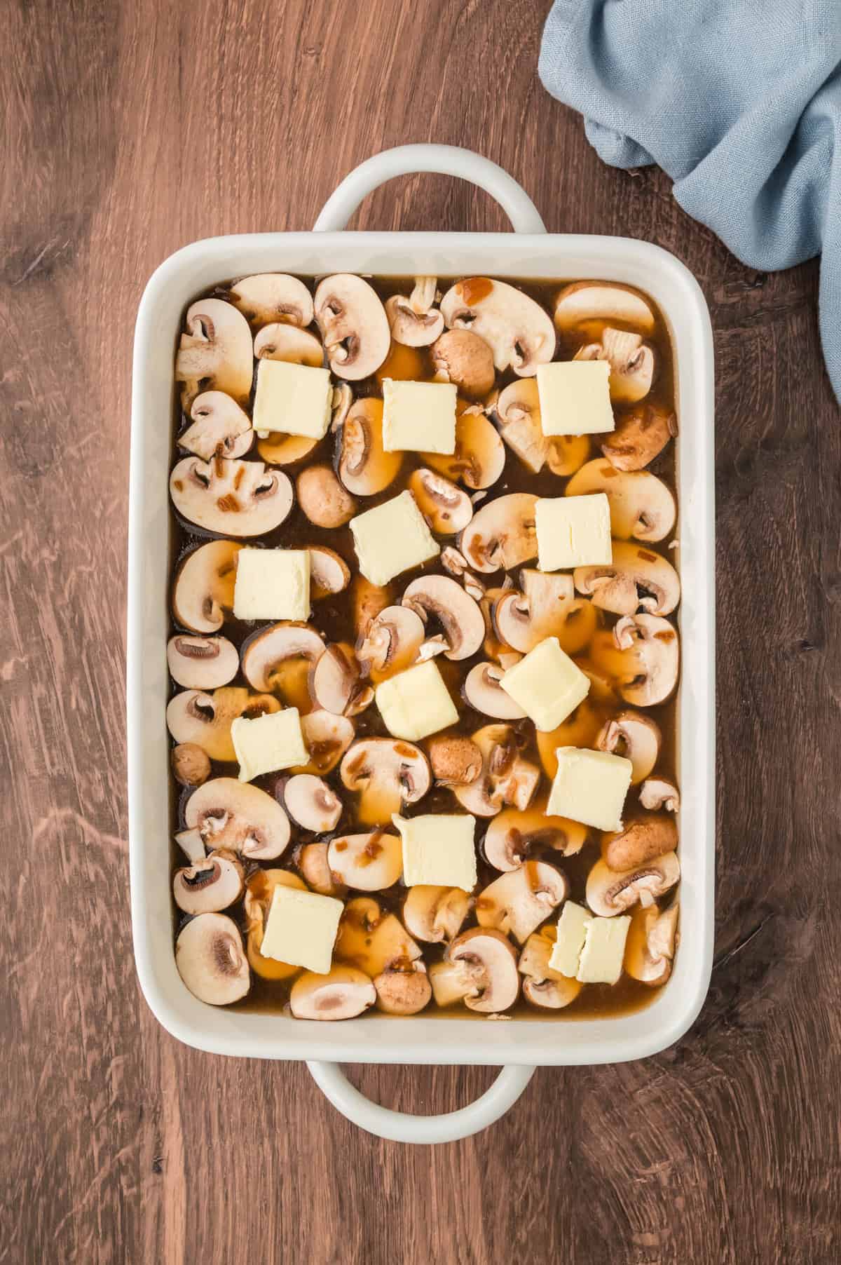 Mushrooms and butter in a bking dish with rice.