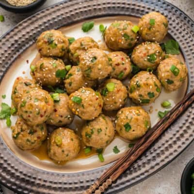 Baked chicken meatballs coated in sesame soy sauce on platter.