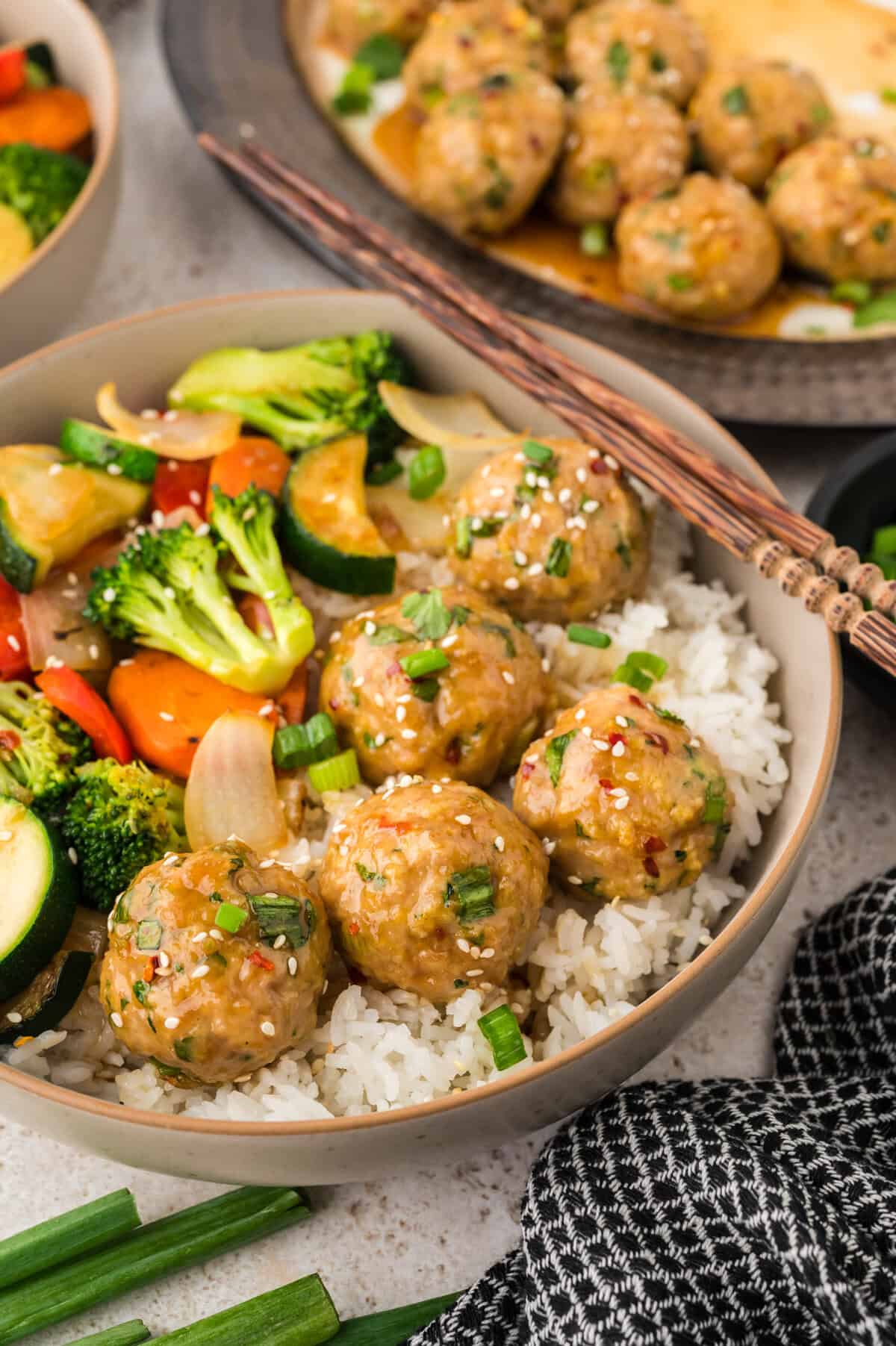Asian chicken meatballs in bowl with rice and vegetables.