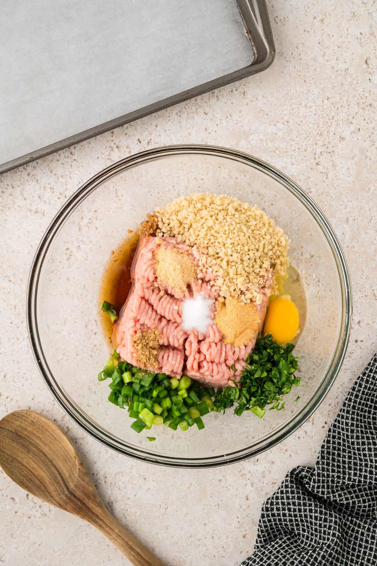 Chicken meatball ingredients in glass mixing bowl.