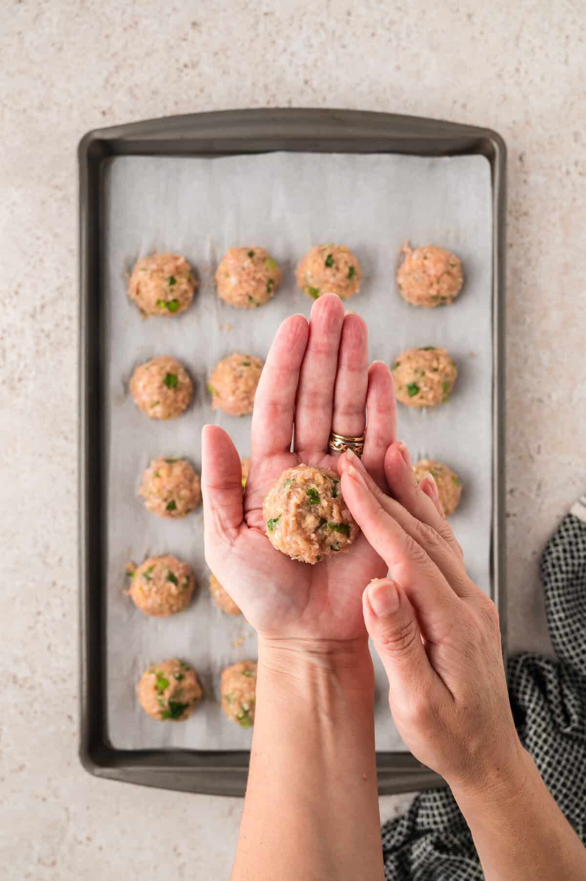Meatballs being rolled by hand.