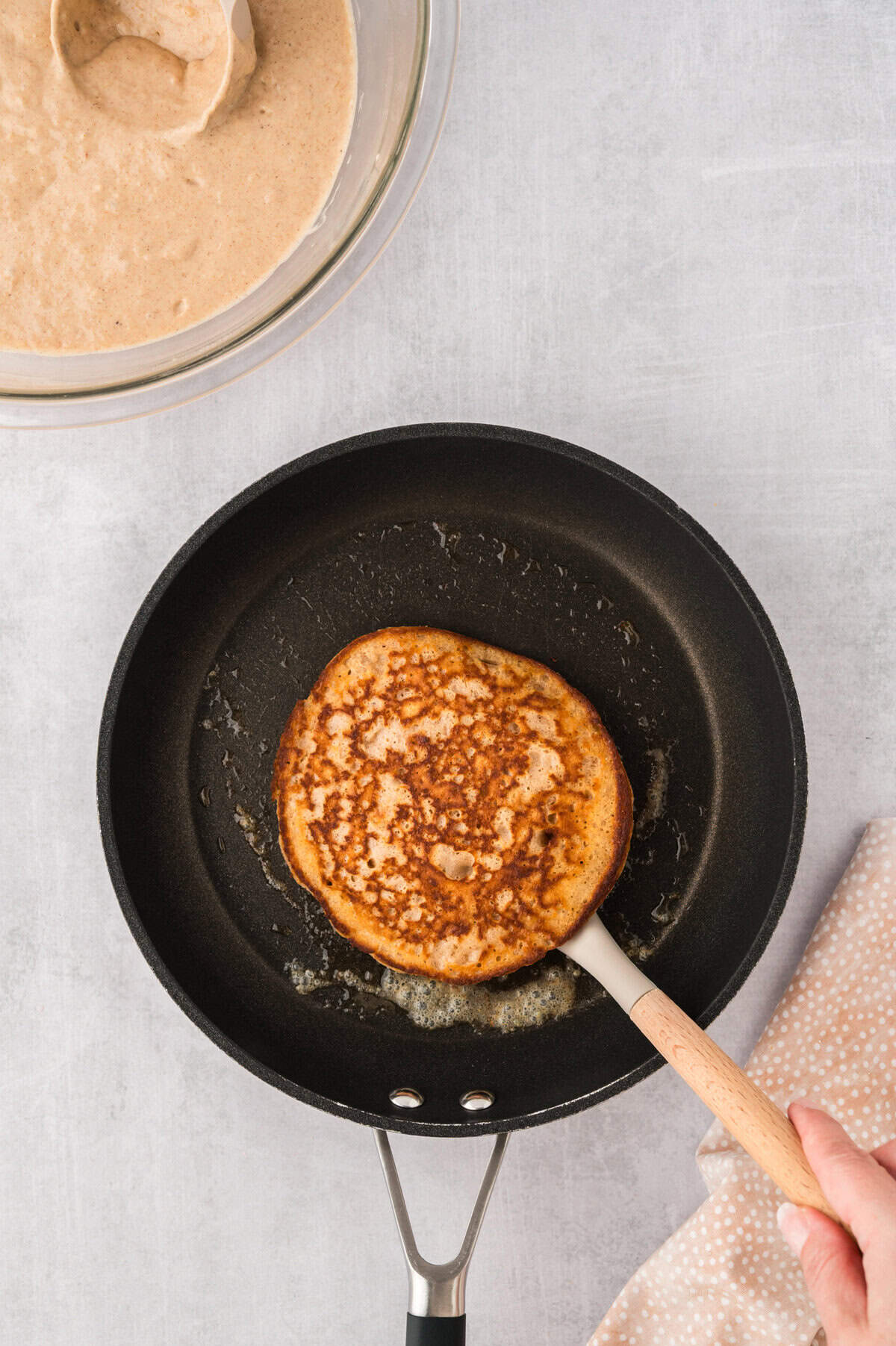 Cooked pancake on spatula in skillet.