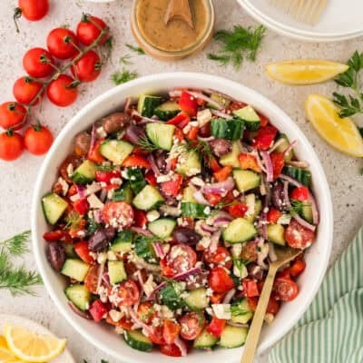 Greek cucumber salad recipe in white bowl with serving spoon.