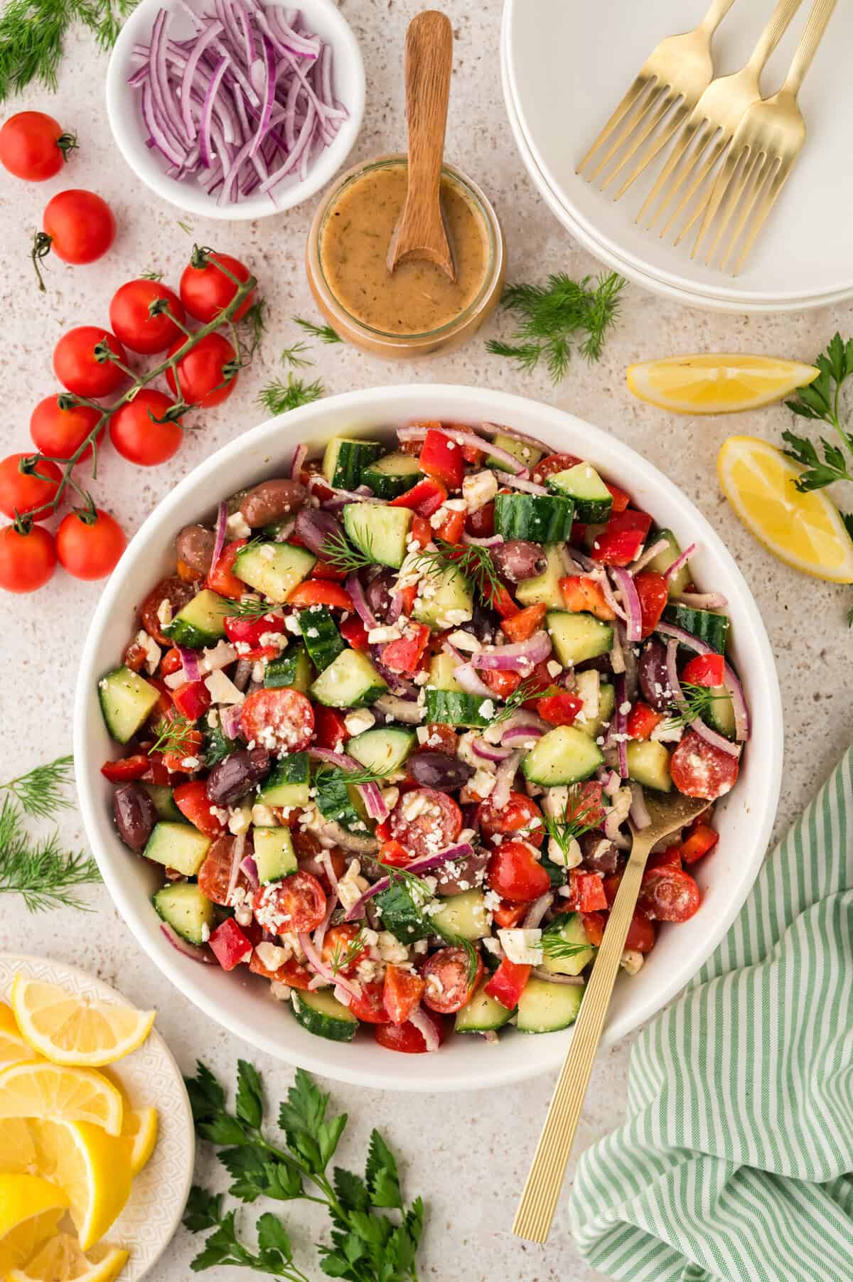 Greek cucumber salad recipe in white bowl with serving spoon.