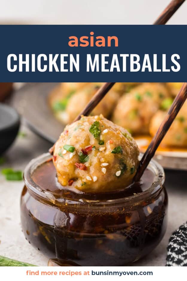 Baked chicken meatball being dunked in soy sesame sauce.