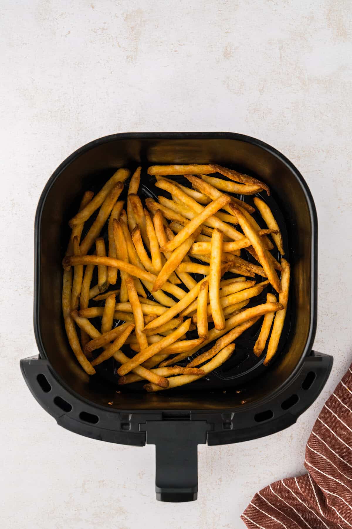 French fries in air fryer basket.