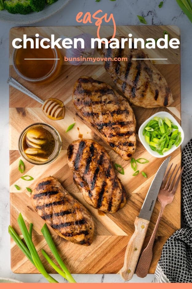 Marinated and grilled chicken breasts on wooden cutting board.