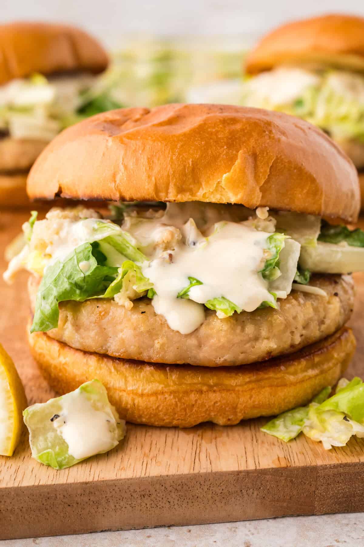 Chicken caesar burger on wooden board.