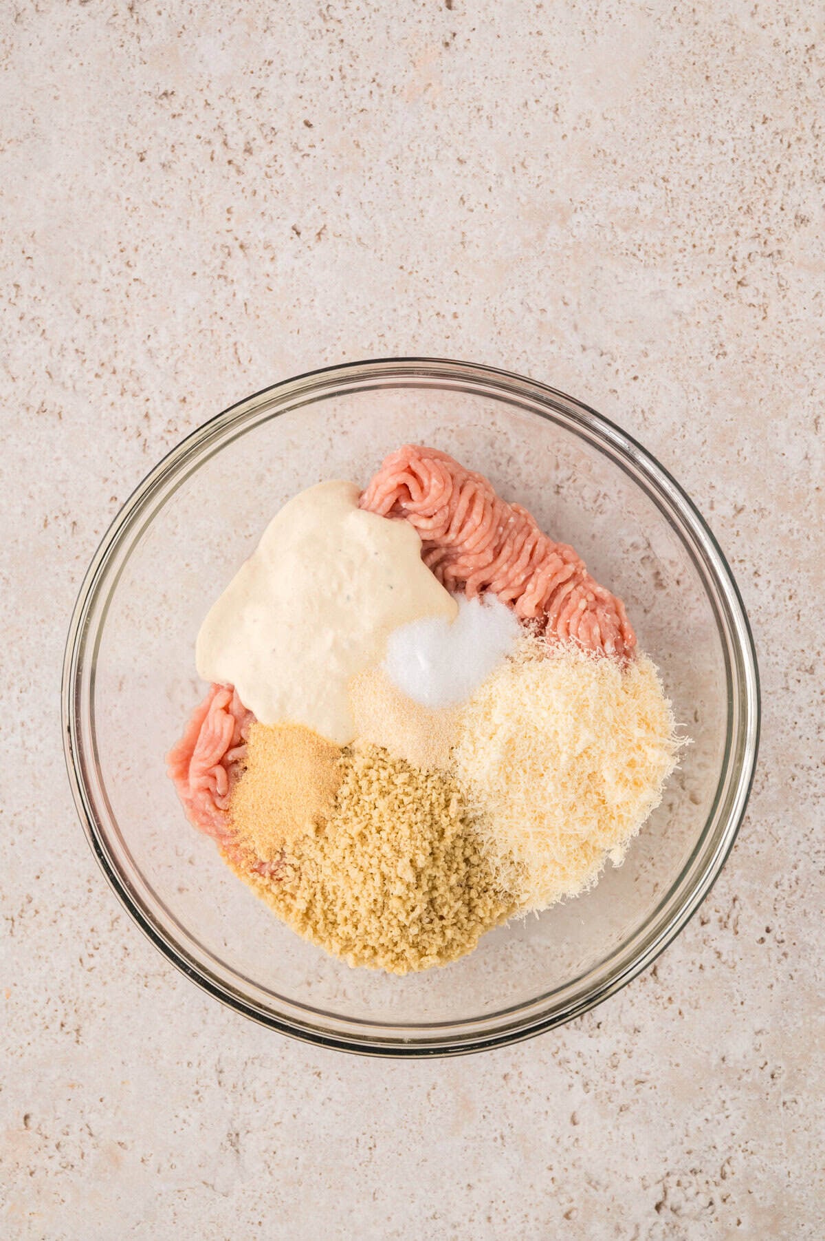 Ingredients for ground chicken Caesar salad burgers in mixing bowl.