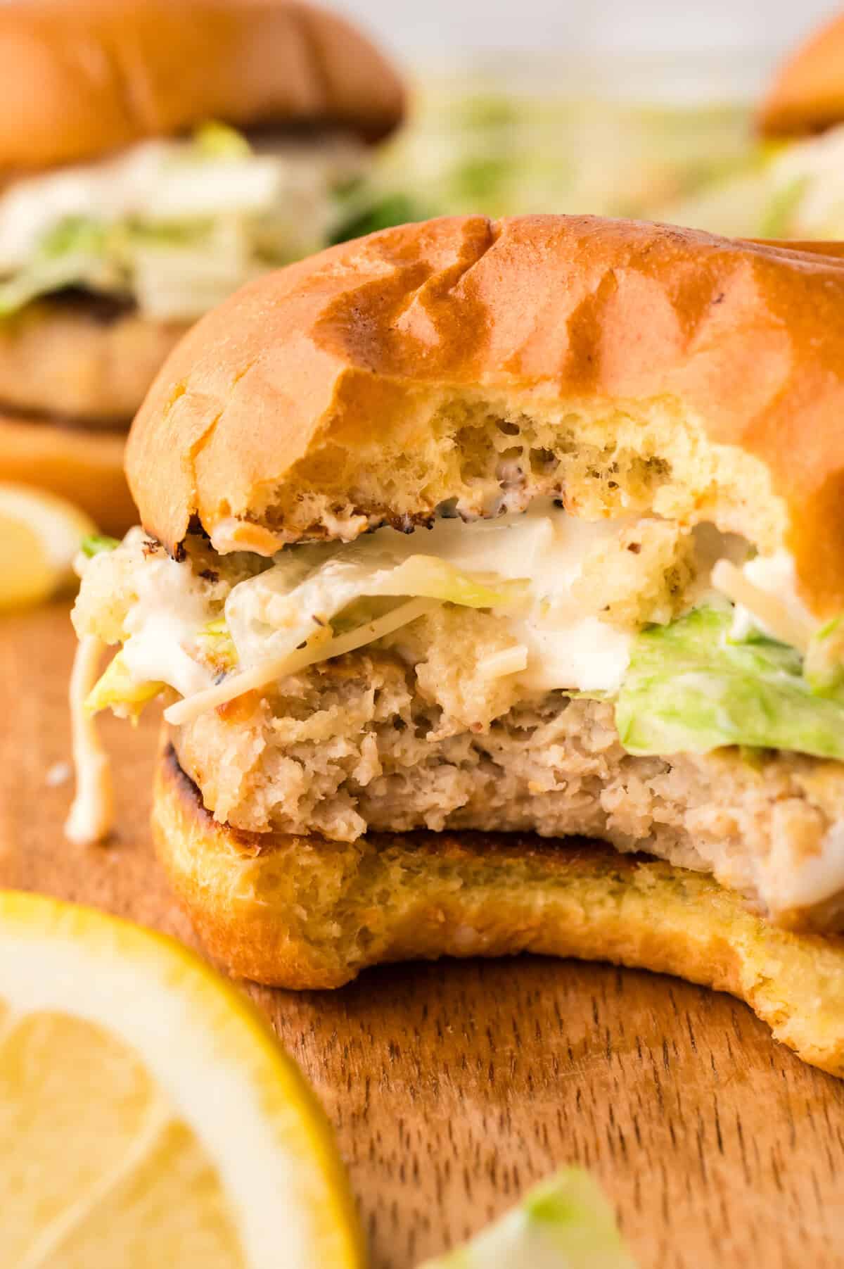 Bite taken out of a chicken Caesar burger.