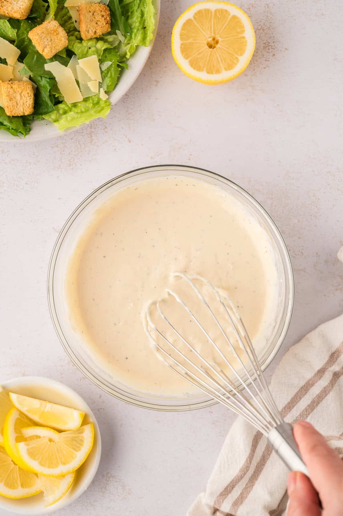 Caesar dressing being whisked together in bowl.