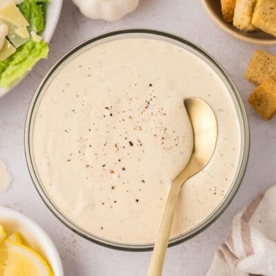 Bowl full of homemade Caesar salad dressing recipe with gold spoon.