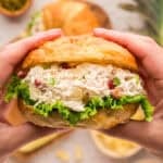 Hands holding a chicken salad sandwich made with bacon, pineapple, and jalapeno.