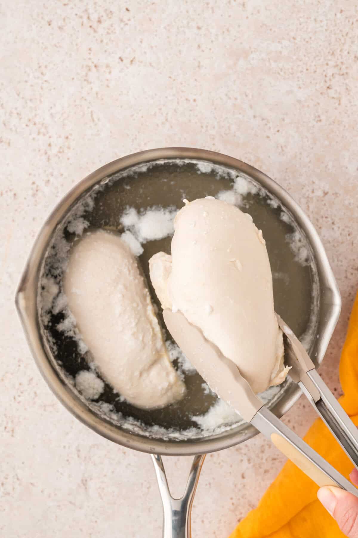 Chicken breasts poached over pot of water.