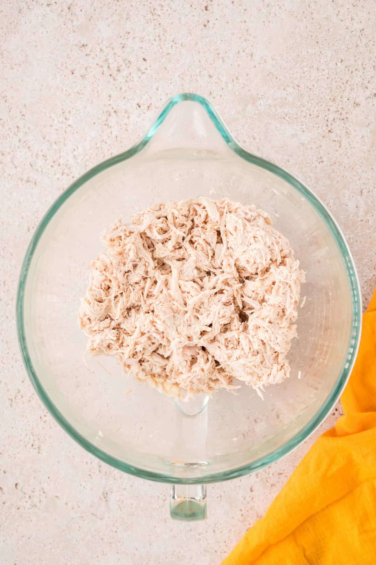 Shredded chicken in mixing bowl.