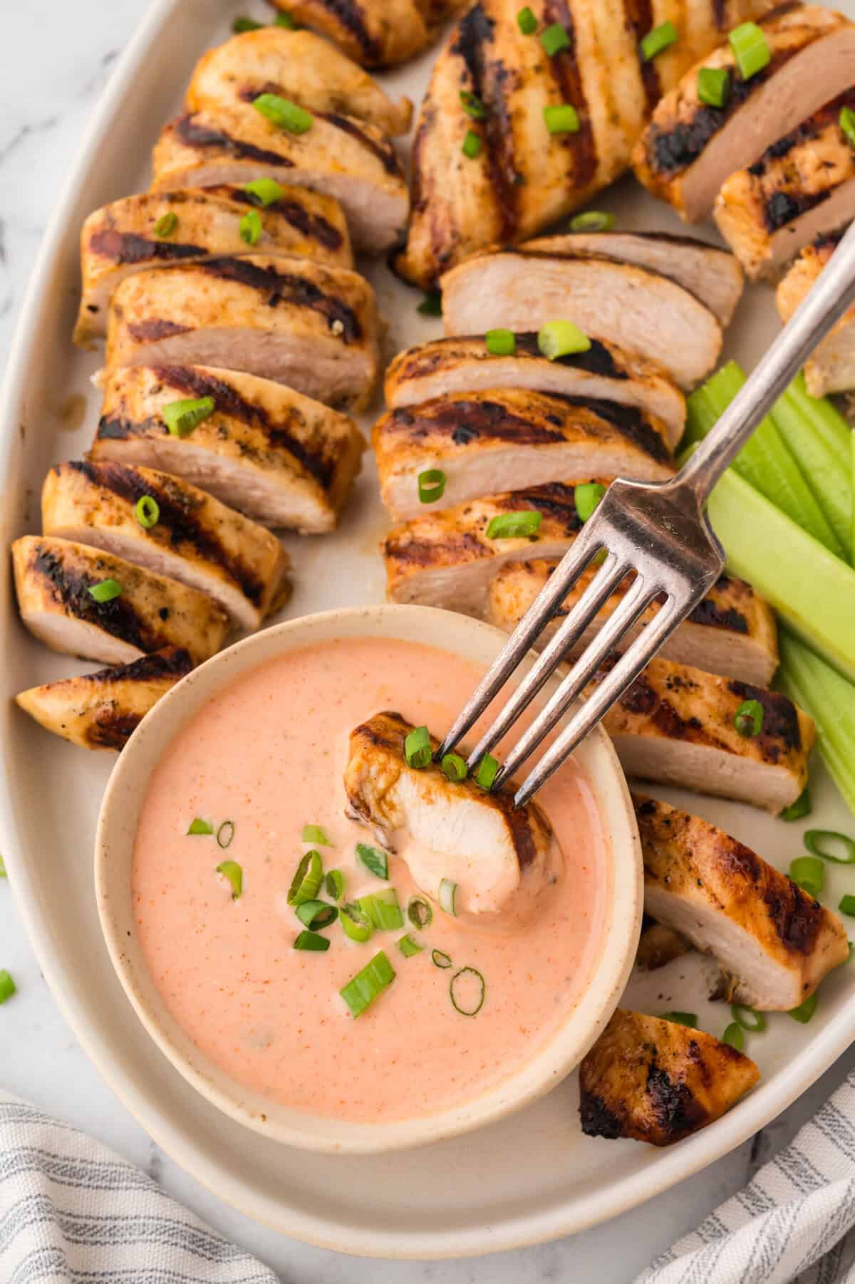 Piece of chicken being dipped in buffalo ranch.