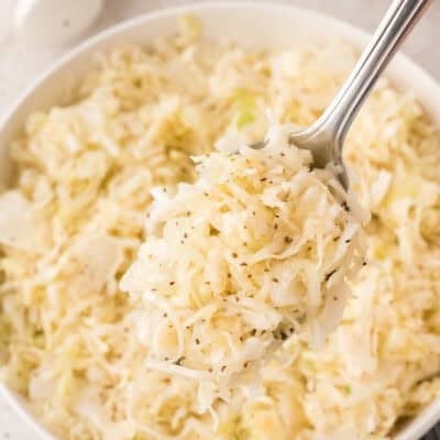 Vinegar coleslaw on spoon over serving bowl.