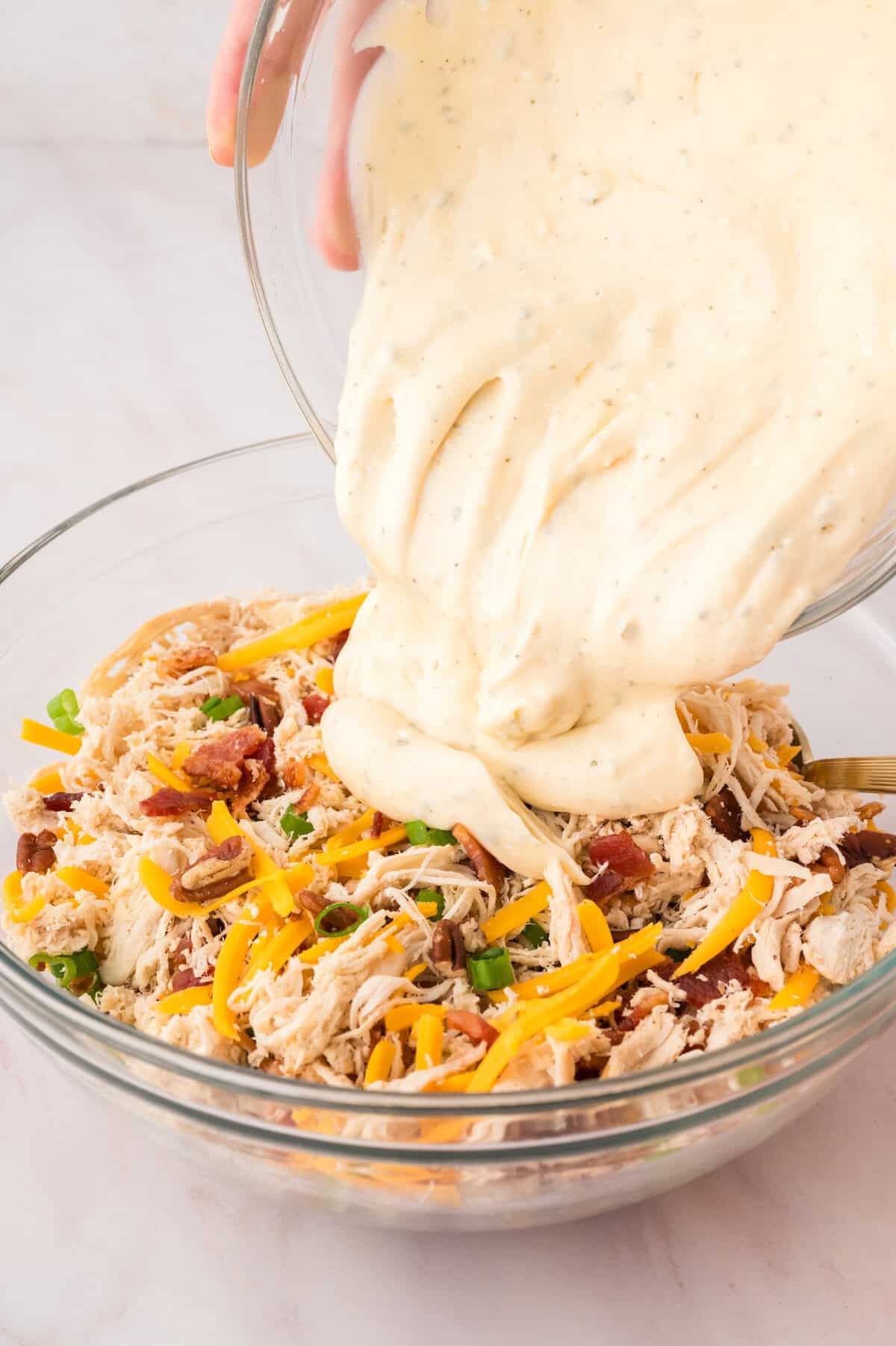 Cream cheese ranch mixture being poured over chicken.