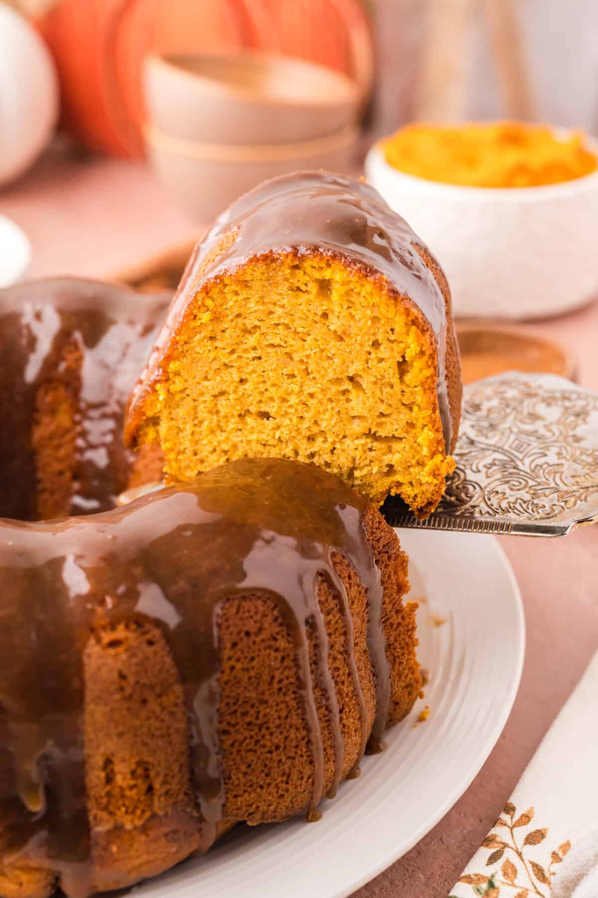 Slice of pumpkin cake being taken off cake plate.