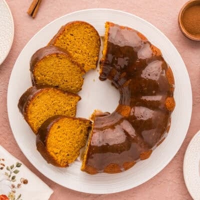 Sliced pumpkin cake with brown sugar glaze on cake plate.