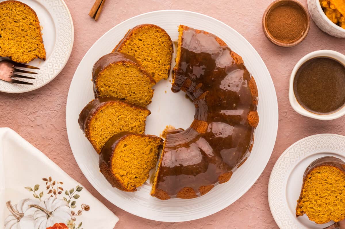 Sliced pumpkin cake with brown sugar glaze on cake plate.