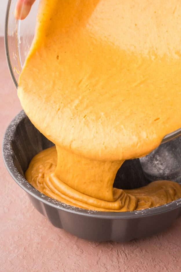 Pumpkin cake batter being poured into bundt pan.